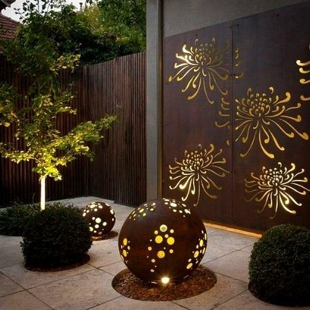 Corten steel garden sculptures and panels lighted from the inside at night