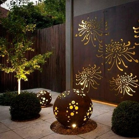 Corten steel garden sculptures and panels lighted from the inside at night